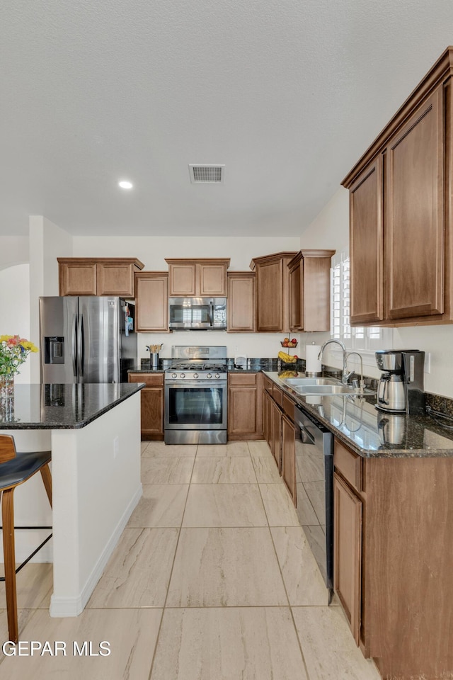 2201 Morning Mist Pl, El Paso, TX 79938 - kitchen featuring appliances with stainless steel finishes, a sink, dark stone countertops, a breakfast bar area, and recessed lighting