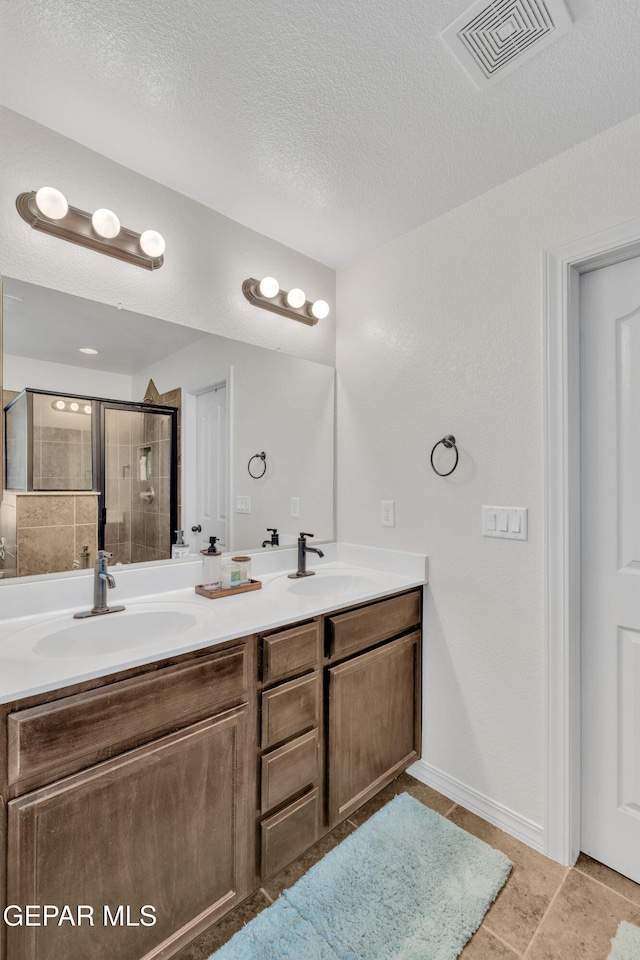 2201 Morning Mist Pl, El Paso, TX 79938 - full bathroom featuring double vanity, a shower stall, a textured ceiling, and baseboards