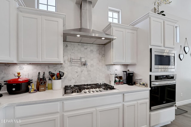 974 Airship Pl, Horizon City, TX 79928 - kitchen featuring stainless steel appliances, wall chimney exhaust hood, white cabinets, decorative backsplash, and light countertops