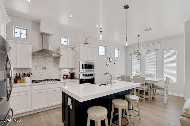 974 Airship Pl, Horizon City, TX 79928 - kitchen featuring appliances with stainless steel finishes, a sink, wall chimney exhaust hood, tasteful backsplash, and a chandelier