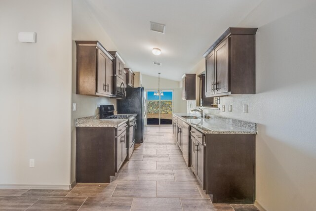 14294 Kayla Mia Dr, El Paso, TX 79938 - kitchen with gas stove, a sink, dark brown cabinetry, stainless steel microwave, and vaulted ceiling