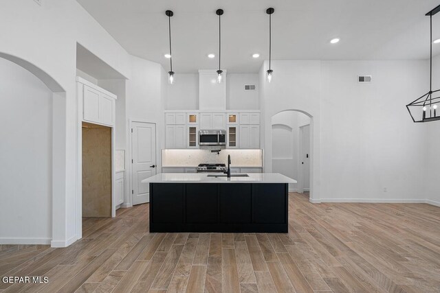 13797 Summer Wave Ave, El Paso, TX 79928 - kitchen featuring appliances with stainless steel finishes, arched walkways, a towering ceiling, light countertops, and a sink