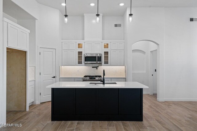 13797 Summer Wave Ave, El Paso, TX 79928 - kitchen featuring appliances with stainless steel finishes, arched walkways, a sink, light countertops, and backsplash