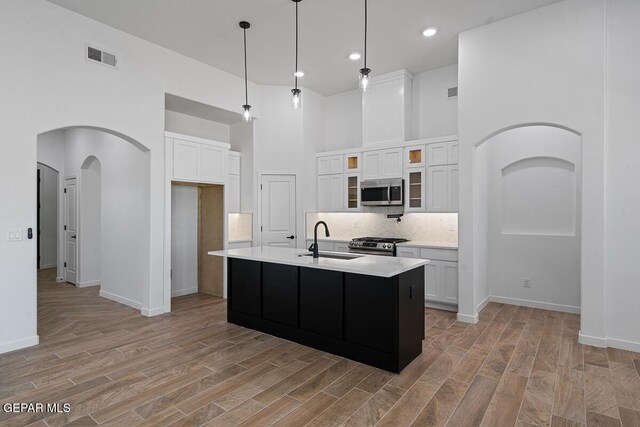 13797 Summer Wave Ave, El Paso, TX 79928 - kitchen featuring stainless steel appliances, a sink, arched walkways, white cabinets, and a high ceiling