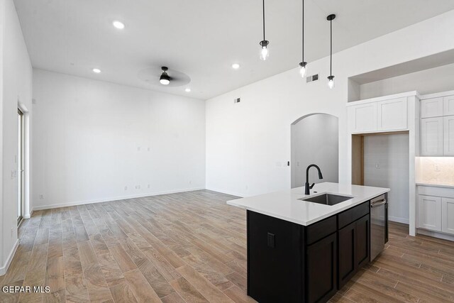13797 Summer Wave Ave, El Paso, TX 79928 - kitchen featuring a sink, arched walkways, dishwasher, light countertops, and light wood finished floors