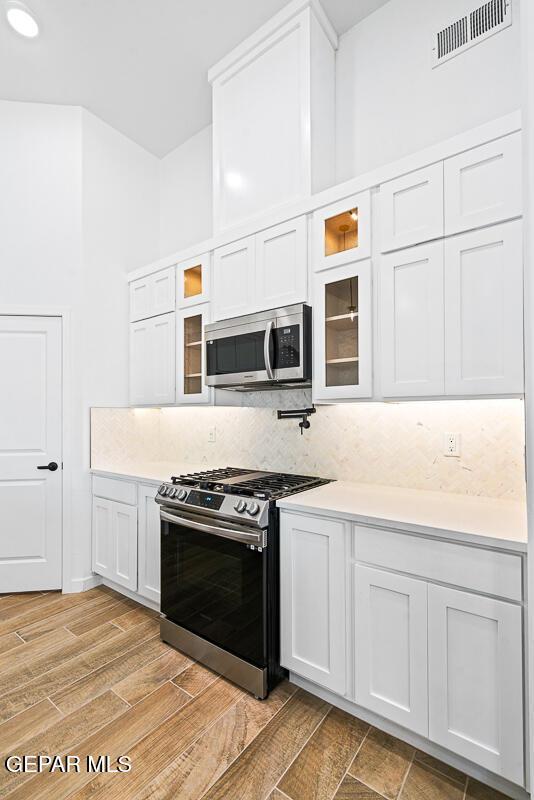 13797 Summer Wave Ave, El Paso, TX 79928 - kitchen with stainless steel appliances, tasteful backsplash, light countertops, and white cabinetry