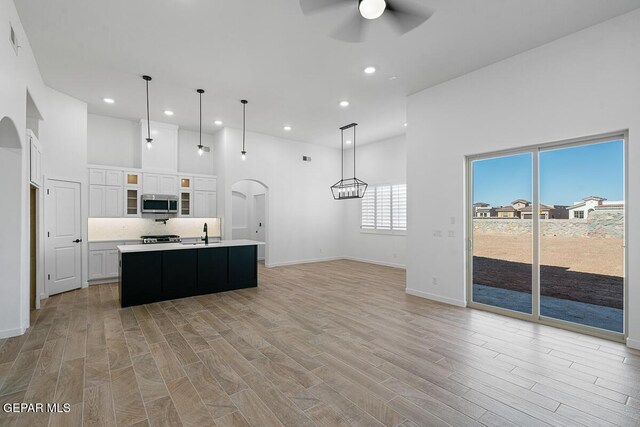 13797 Summer Wave Ave, El Paso, TX 79928 - kitchen featuring stainless steel microwave, arched walkways, ceiling fan, light countertops, and a high ceiling