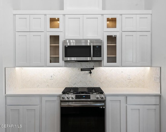 13797 Summer Wave Ave, El Paso, TX 79928 - kitchen featuring stainless steel appliances, light countertops, glass insert cabinets, and backsplash
