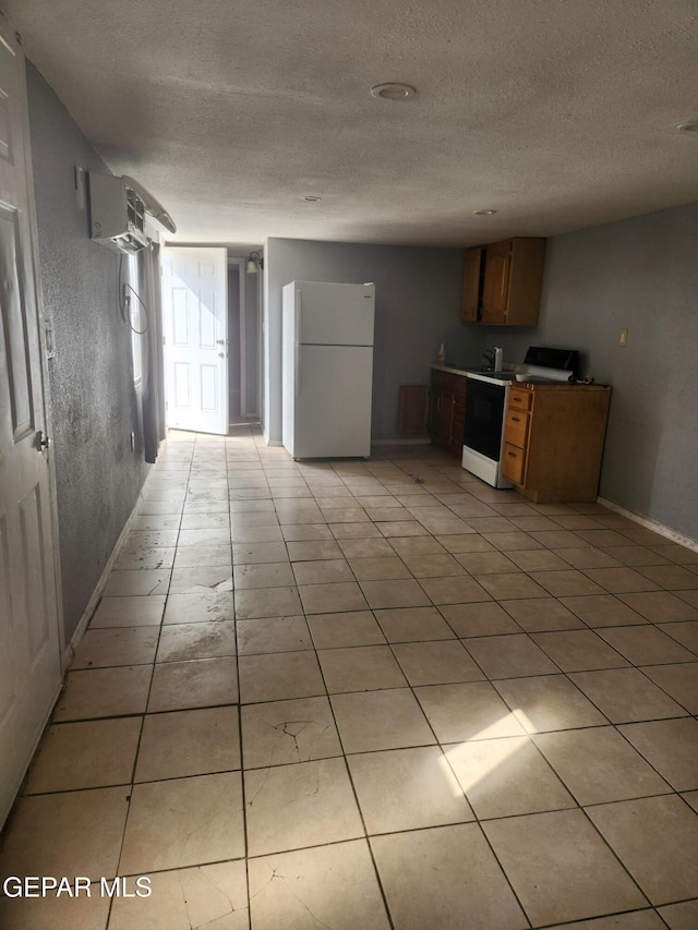 7511 Howard St, El Paso, TX 79904 - kitchen featuring freestanding refrigerator, electric range oven, a textured ceiling, baseboards, and light tile patterned floors