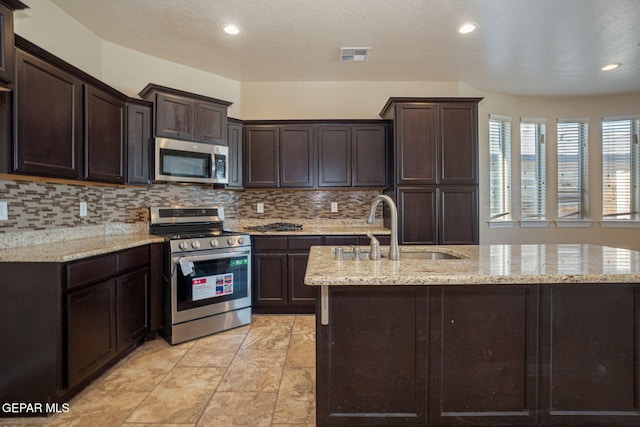 117 Camino Cresta Pl, Horizon City, TX 79928 - kitchen with stainless steel appliances, a sink, tasteful backsplash, dark brown cabinetry, and recessed lighting