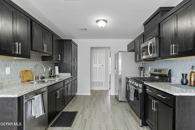 13142 Emerald Isle St, El Paso, TX 79928 - kitchen featuring appliances with stainless steel finishes, tasteful backsplash, dark cabinets, and light stone countertops