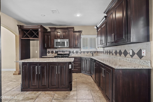 2909 Pino Triste Dr, El Paso, TX 79938 - kitchen with appliances with stainless steel finishes, backsplash, dark brown cabinetry, a kitchen island, and recessed lighting