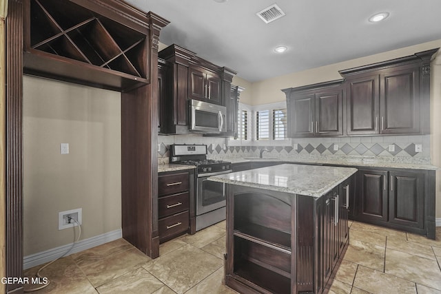 2909 Pino Triste Dr, El Paso, TX 79938 - kitchen with stainless steel appliances, open shelves, decorative backsplash, light stone counters, and dark brown cabinetry