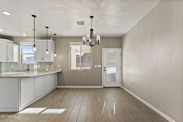 6037 Vicente Gomez Ln, El Paso, TX 79932 - kitchen featuring baseboards, light wood-style flooring, white cabinets, a chandelier, and tasteful backsplash