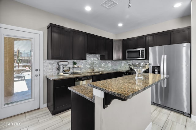 3452 David Palacio Dr, El Paso, TX 79938 - kitchen with appliances with stainless steel finishes, dark stone countertops, a kitchen island, tasteful backsplash, and recessed lighting
