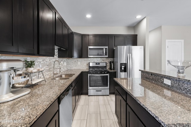 3452 David Palacio Dr, El Paso, TX 79938 - kitchen with appliances with stainless steel finishes, decorative backsplash, stone counters, dark cabinetry, and recessed lighting