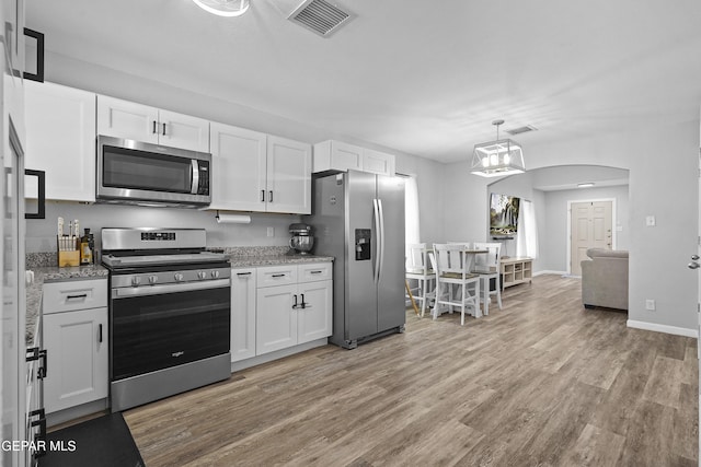 14236 Rattler Point Dr, El Paso, TX 79938 - kitchen with stainless steel appliances, white cabinetry, light wood-type flooring, and arched walkways