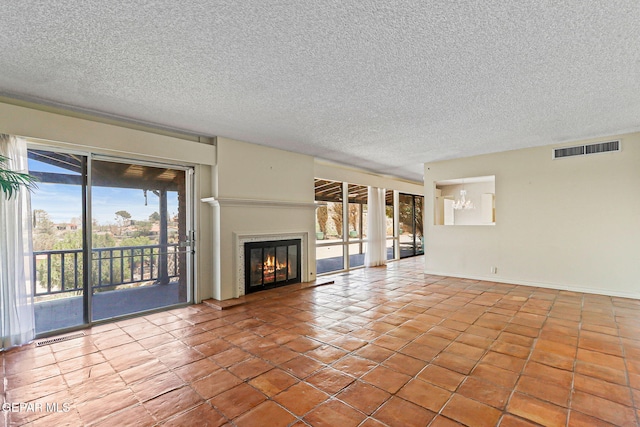 3134 Mesa Verde Ln, El Paso, TX 79904 - unfurnished living room featuring a chandelier, a glass covered fireplace, a textured ceiling, tile patterned floors, and baseboards