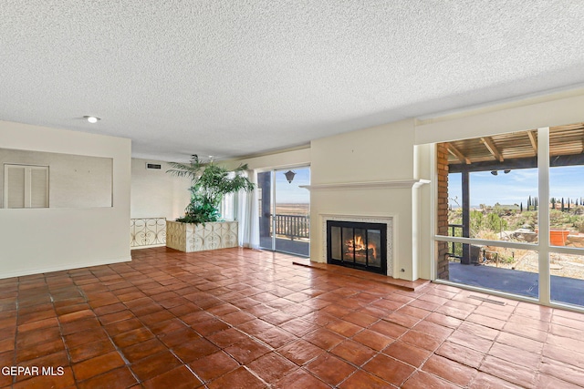 3134 Mesa Verde Ln, El Paso, TX 79904 - unfurnished living room with plenty of natural light, tile patterned floors, a glass covered fireplace, a textured ceiling, and baseboards