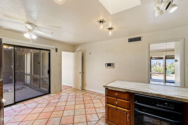3134 Mesa Verde Ln, El Paso, TX 79904 - kitchen featuring oven, tile counters, a ceiling fan, brown cabinetry, and a textured ceiling