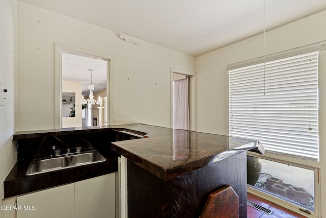 3134 Mesa Verde Ln, El Paso, TX 79904 - kitchen with dark countertops, a sink, decorative light fixtures, and a chandelier