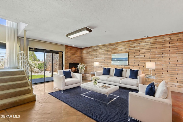 3134 Mesa Verde Ln, El Paso, TX 79904 - living room featuring brick wall, stairway, a textured ceiling, and a brick fireplace