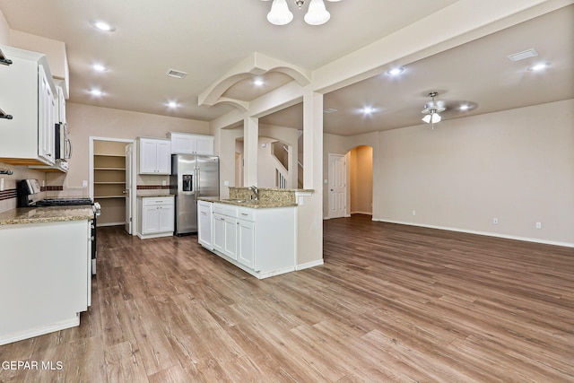 14840 Tim Hardaway, El Paso, TX 79938 - kitchen featuring appliances with stainless steel finishes, arched walkways, open floor plan, light wood-style floors, and white cabinets