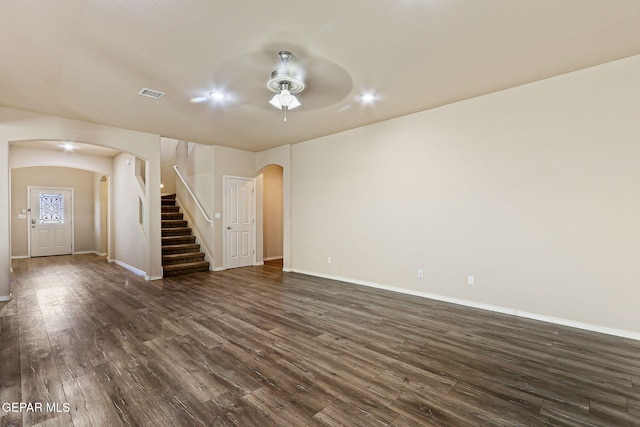 14840 Tim Hardaway, El Paso, TX 79938 - unfurnished living room with arched walkways, stairway, dark wood-style flooring, a ceiling fan, and baseboards