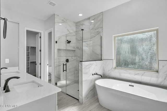 248 Emerald Storm Pl, El Paso, TX 79928 - full bathroom featuring a marble finish shower, a soaking tub, toilet, double vanity, and tile walls