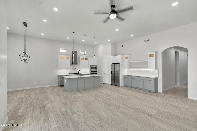 248 Emerald Storm Pl, El Paso, TX 79928 - kitchen with wall chimney range hood, stainless steel fridge, a sink, arched walkways, and light countertops