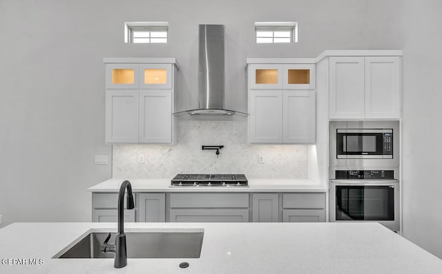 248 Emerald Storm Pl, El Paso, TX 79928 - kitchen featuring appliances with stainless steel finishes, wall chimney range hood, a sink, and glass insert cabinets