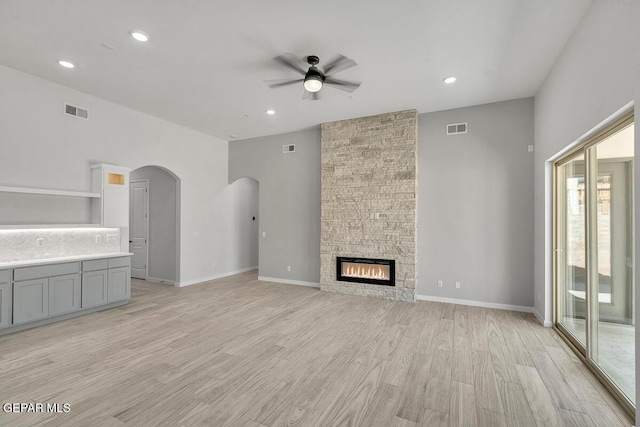 248 Emerald Storm Pl, El Paso, TX 79928 - unfurnished living room featuring a ceiling fan, light wood-style flooring, arched walkways, recessed lighting, and a stone fireplace