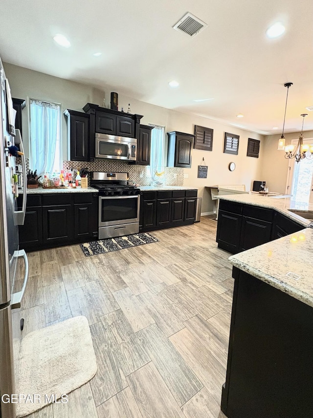 12217 Chapel Hill Rd, El Paso, TX 79928 - kitchen featuring stainless steel appliances, dark cabinetry, decorative backsplash, recessed lighting, and light stone counters