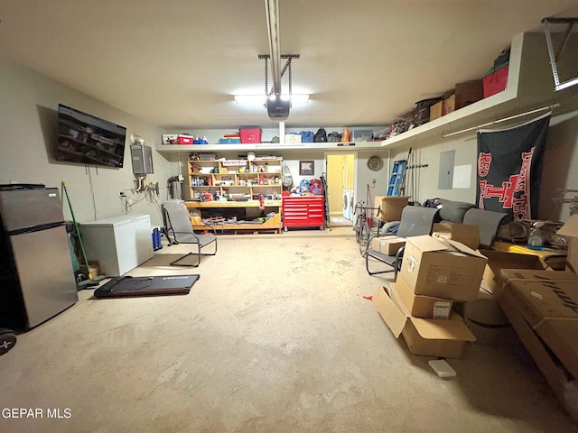 12217 Chapel Hill Rd, El Paso, TX 79928 - garage featuring freestanding refrigerator, a garage door opener, electric panel, and refrigerator