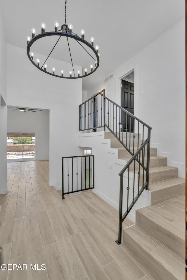 1460 Backus St, El Paso, TX 79925 - stairs with a chandelier, wood finished floors, ceiling fan, and baseboards