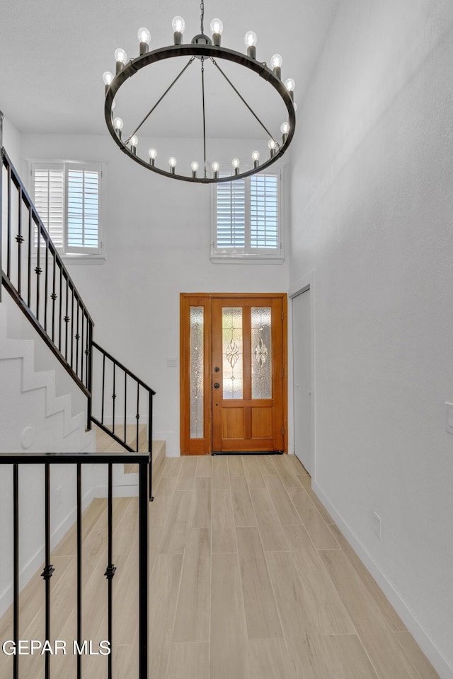 1460 Backus St, El Paso, TX 79925 - foyer entrance with a chandelier, stairs, a high ceiling, baseboards, and wood finished floors