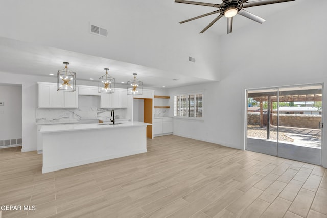1460 Backus St, El Paso, TX 79925 - unfurnished living room featuring a sink, ceiling fan, light wood-style flooring, baseboards, and a towering ceiling