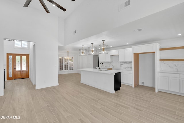 1460 Backus St, El Paso, TX 79925 - kitchen featuring a sink, white cabinetry, tasteful backsplash, a kitchen island with sink, and light countertops