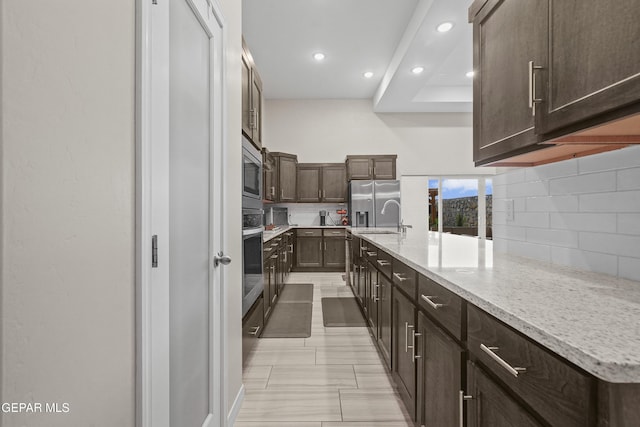2305 Enchanted Quail, El Paso, TX 79911 - kitchen with backsplash, dark brown cabinetry, appliances with stainless steel finishes, recessed lighting, and light stone countertops