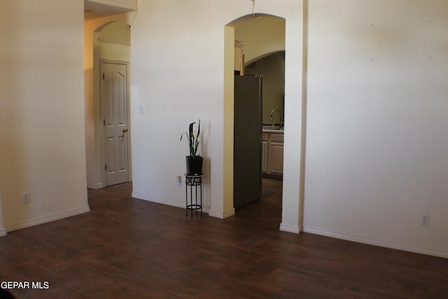 1429 Jettie Ray Way, El Paso, TX 79936 - unfurnished room with arched walkways, dark wood-type flooring, baseboards, and a sink