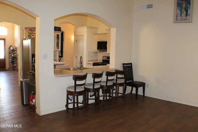1429 Jettie Ray Way, El Paso, TX 79936 - kitchen with gas stove, a sink, dark wood finished floors, a breakfast bar area, and backsplash