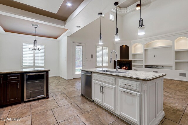 3081 Coyote Point Pl, El Paso, TX 79938 - kitchen featuring beverage cooler, stainless steel dishwasher, a lit fireplace, a chandelier, and built in shelves