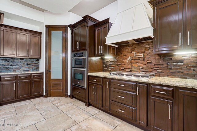 3081 Coyote Point Pl, El Paso, TX 79938 - kitchen with custom range hood, stainless steel appliances, backsplash, and dark brown cabinets