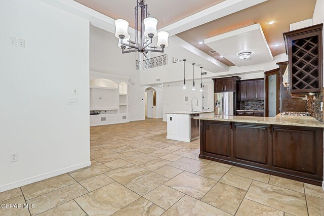 3081 Coyote Point Pl, El Paso, TX 79938 - kitchen featuring stainless steel appliances, a peninsula, dark brown cabinetry, a chandelier, and hanging light fixtures