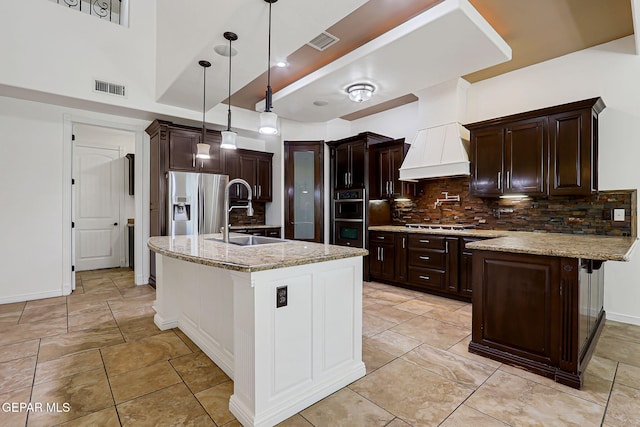 3081 Coyote Point Pl, El Paso, TX 79938 - kitchen with premium range hood, backsplash, stainless steel fridge, a peninsula, and dark brown cabinetry