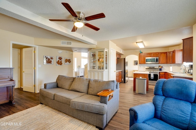 13261 Walker Post Ave, El Paso, TX 79928 - living area featuring arched walkways, wood finished floors, ceiling fan, and a textured ceiling