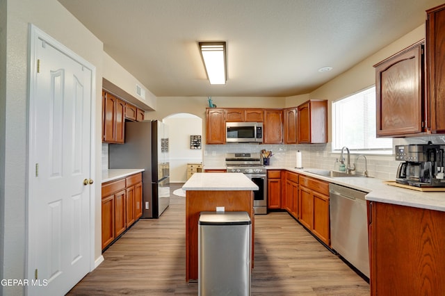 13261 Walker Post Ave, El Paso, TX 79928 - kitchen with stainless steel appliances, arched walkways, decorative backsplash, a center island, and light wood-type flooring
