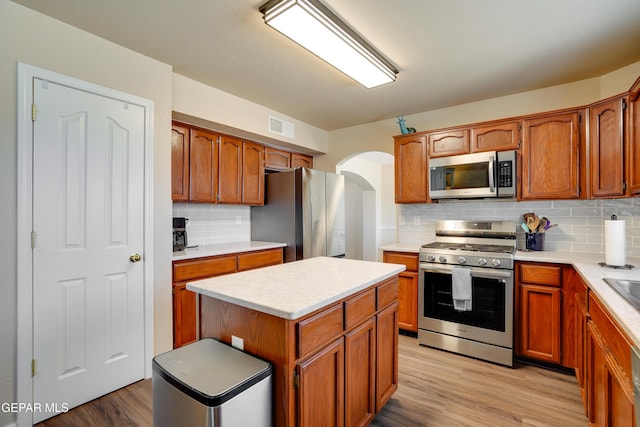 13261 Walker Post Ave, El Paso, TX 79928 - kitchen with stainless steel appliances, arched walkways, decorative backsplash, light countertops, and light wood-type flooring