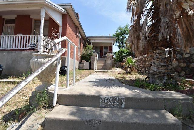 1275 Prospect St, El Paso, TX 79902 - view of side of home featuring covered porch, brick siding, and stairway