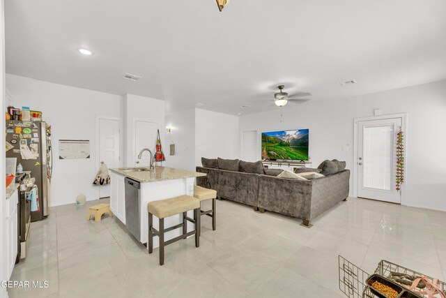 14423 Kayla Mia Dr, El Paso, TX 79938 - kitchen with appliances with stainless steel finishes, a sink, light stone countertops, ceiling fan, and a breakfast bar area